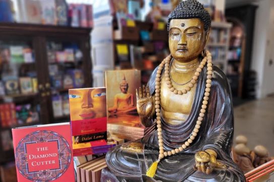 A bronze statue of Buddha next to various books on Buddhism