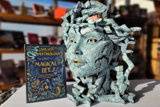A statue of Medusa's head next to a book about mythology