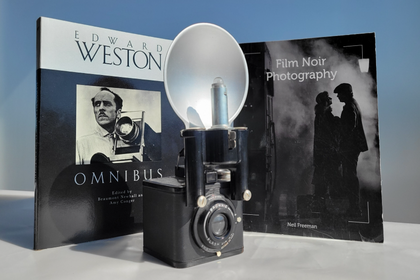 An old fashioned camera in front of a book about film noir photography